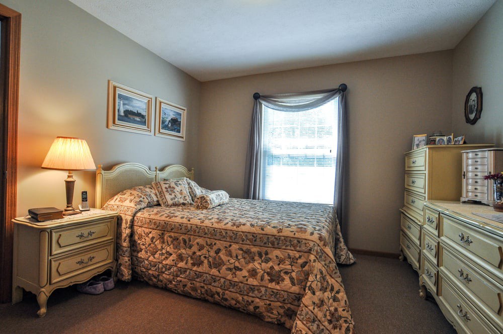 A cozy bedroom with a patterned bedspread, side tables, and a window allowing natural light.