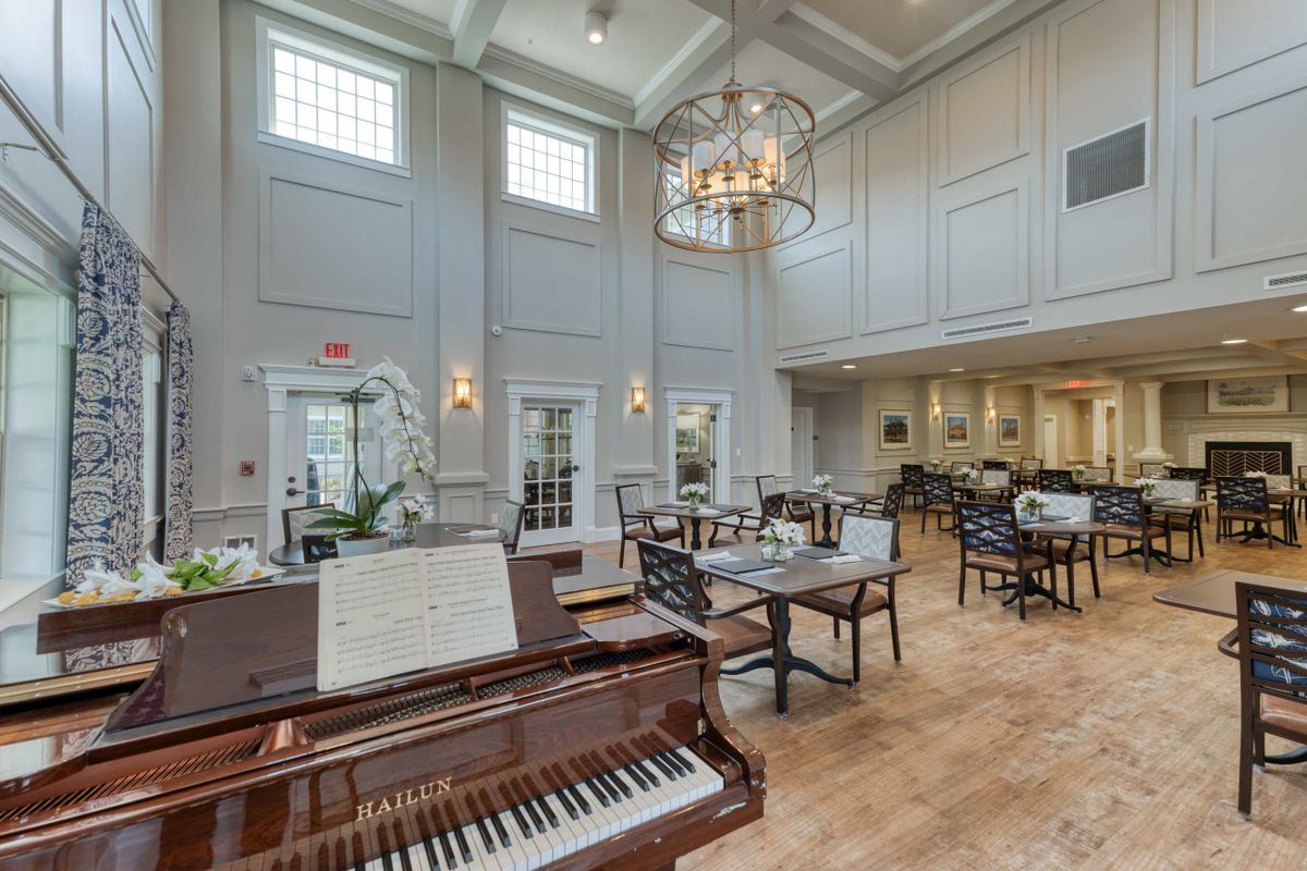 An elegant dining area with a grand piano and chandelier.