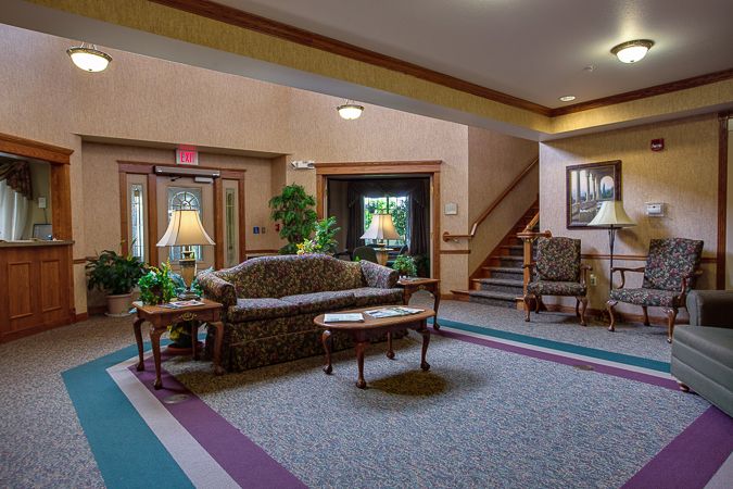 A cozy lobby area featuring a sofa, tables, and decorative plants.