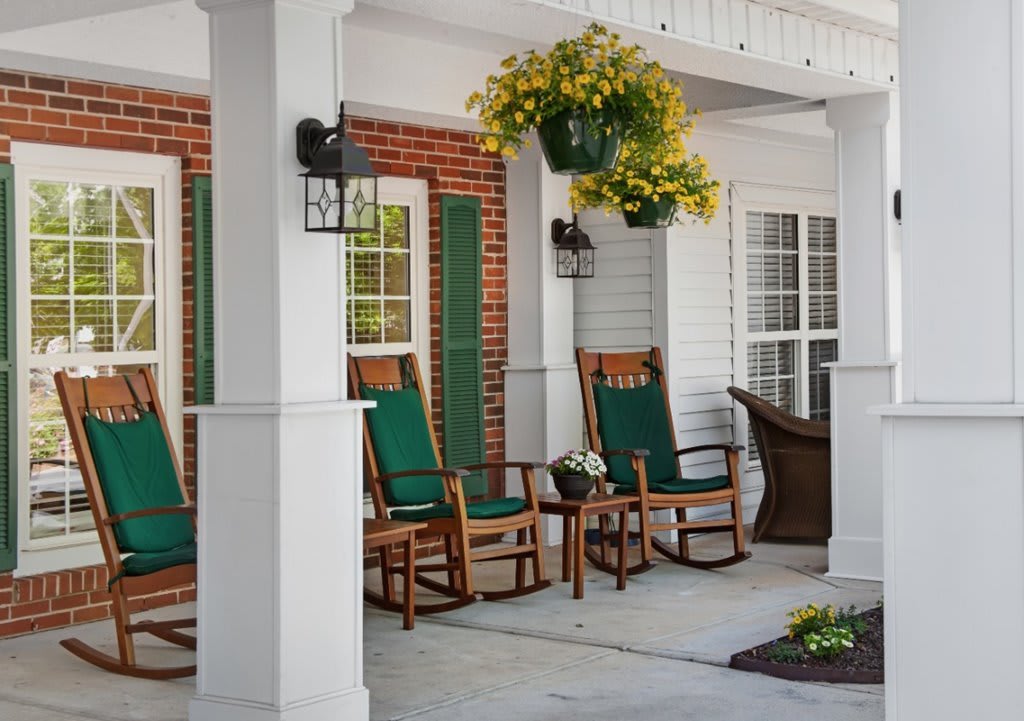 A cozy porch with rocking chairs and hanging plants.
