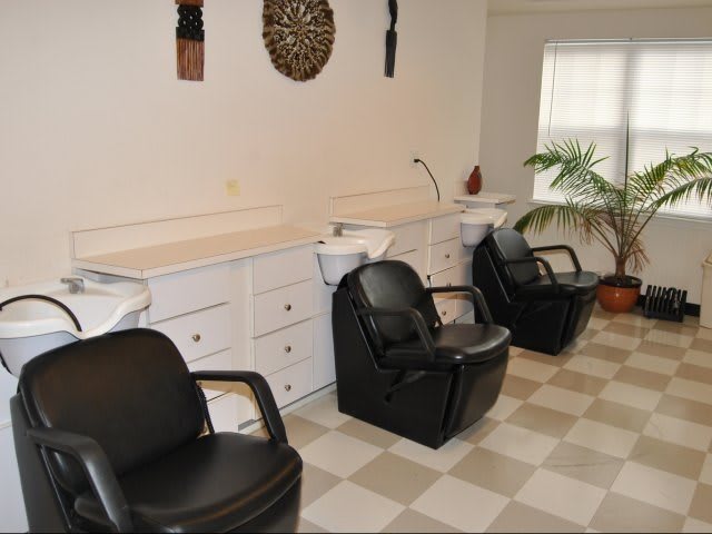An interior view of a hair salon with black chairs and washing stations.
