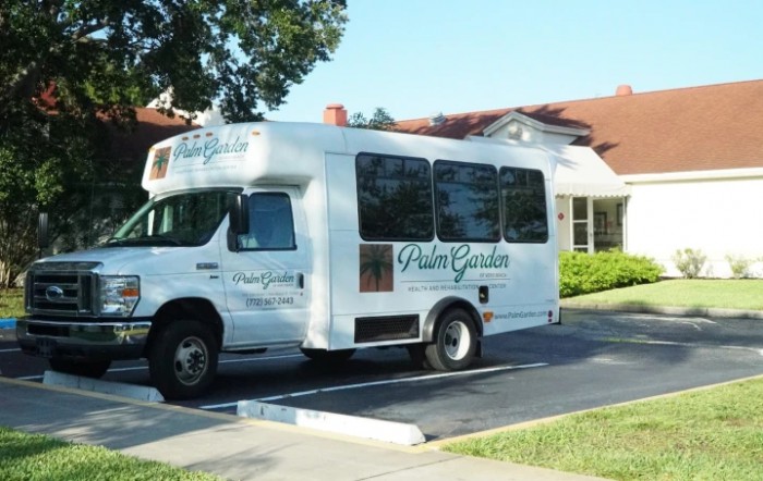 A shuttle bus parked in front of a building with trees in the background.