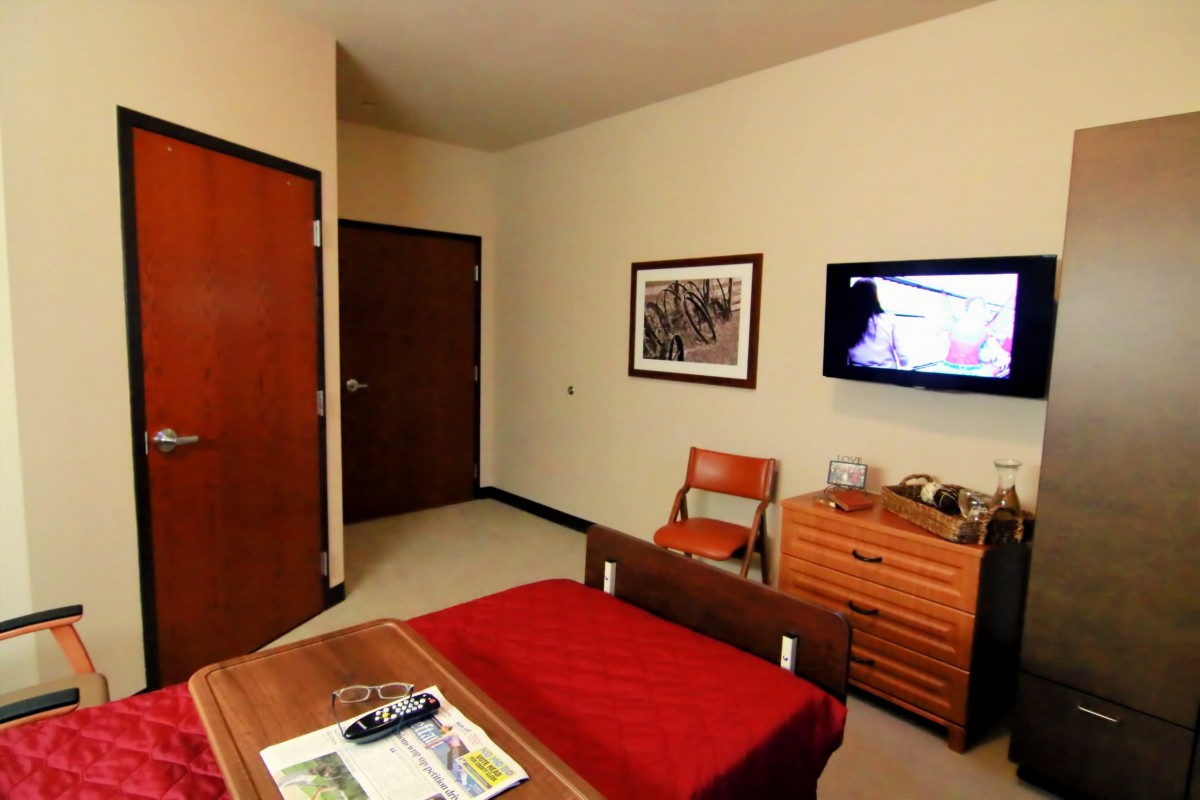 Cozy hotel room interior with a bed, television, and wooden furniture.