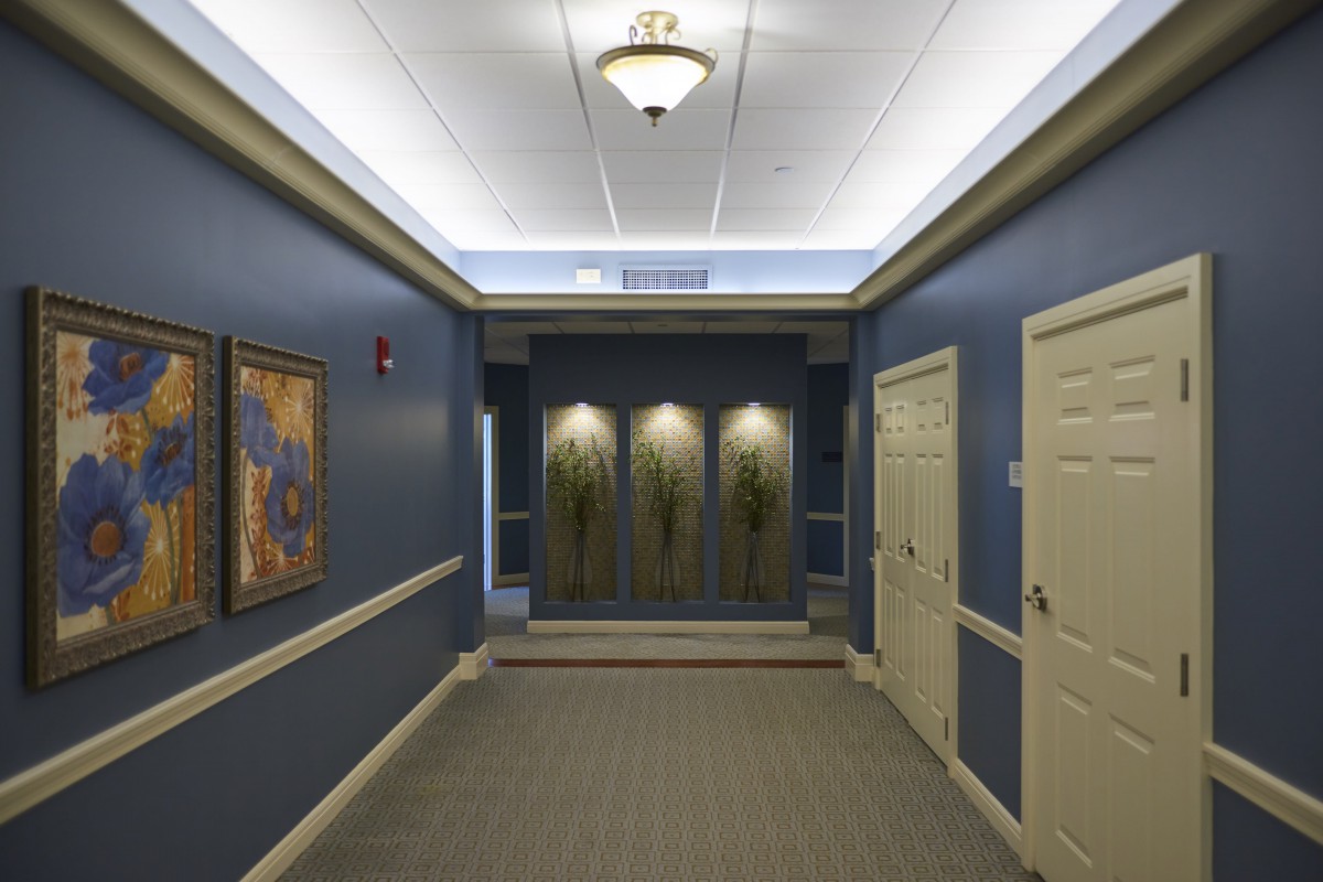 A well-lit hallway with blue walls and an elevator at the end.