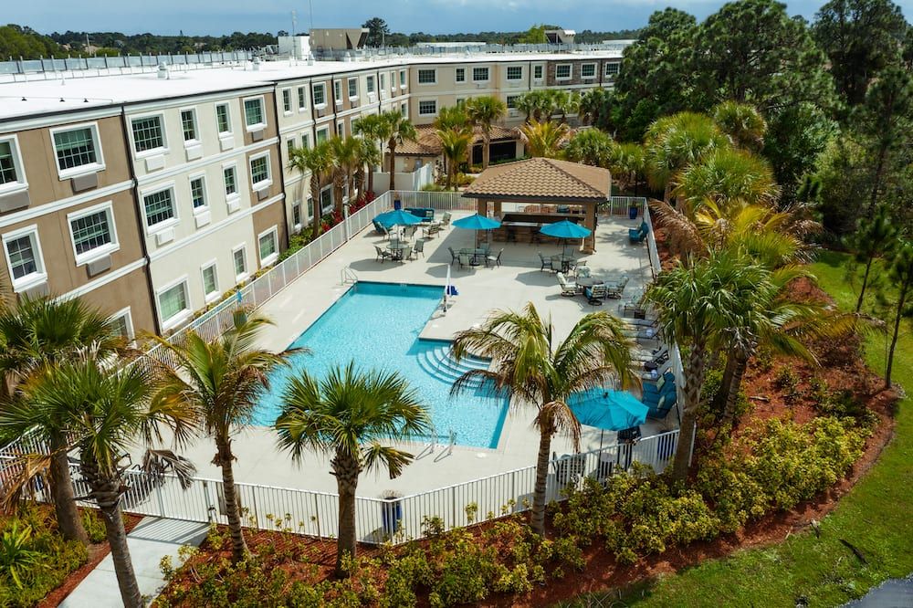 Aerial view of an apartment complex with a swimming pool and palm trees.