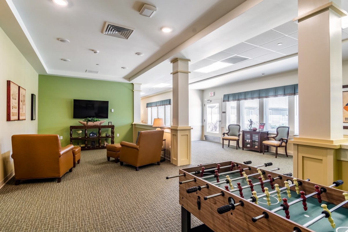 A spacious game room featuring a foosball table, comfortable seating, and a television for entertainment.
