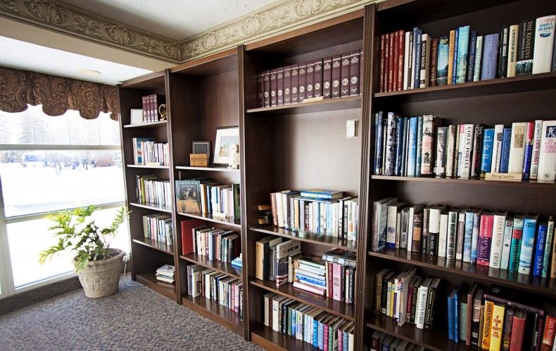 A cozy home library with wooden bookshelves filled with a variety of books.