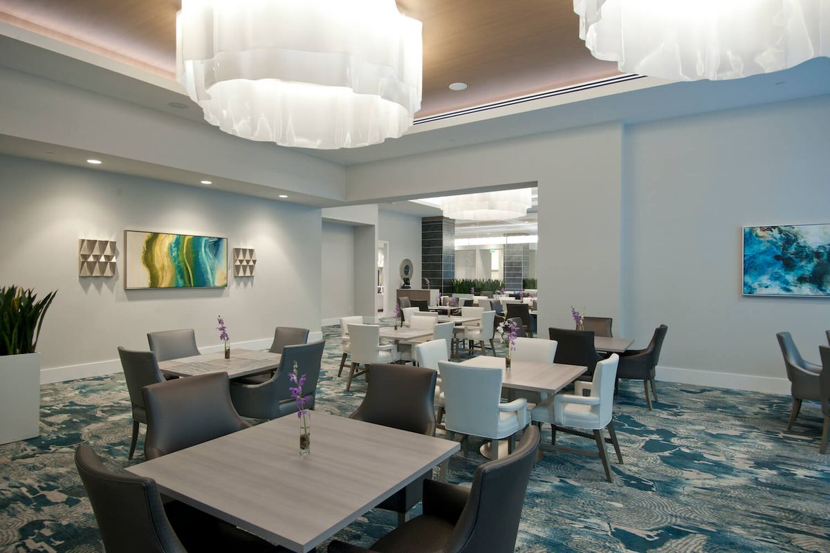 A modern dining area featuring elegant furniture, contemporary lighting, and colorful artwork.