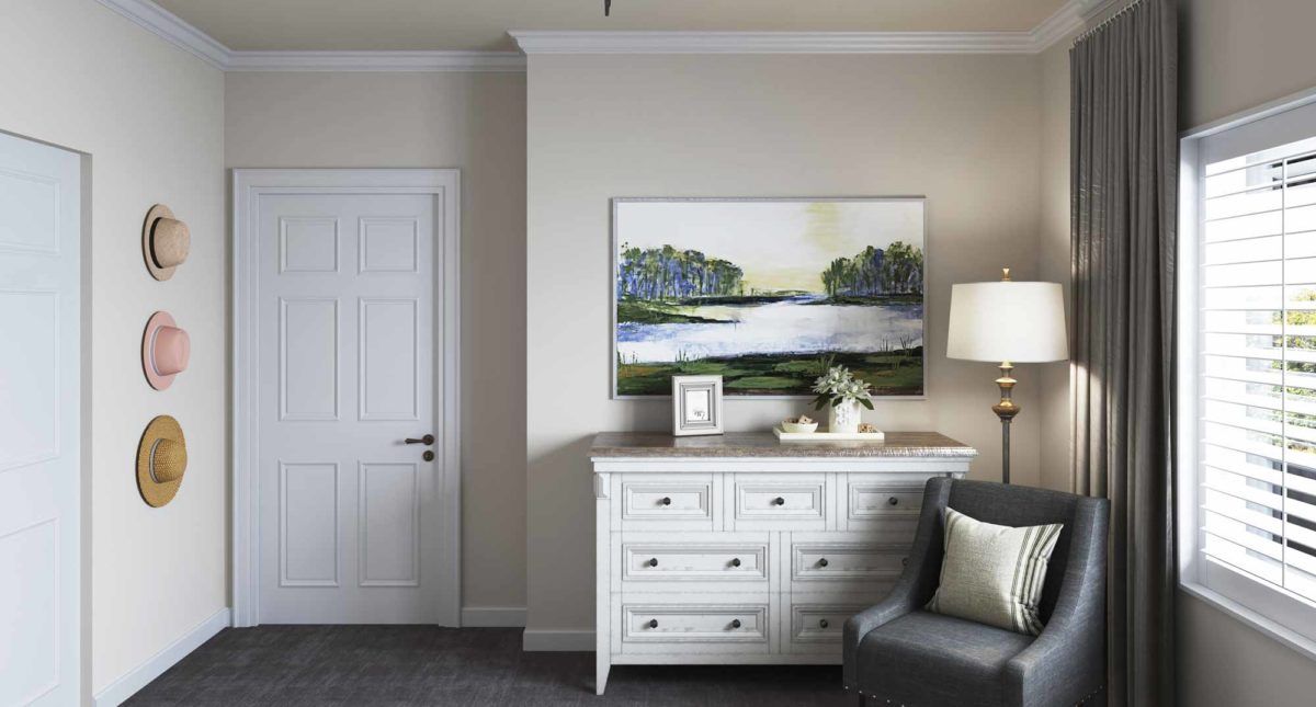 A cozy bedroom interior featuring a white dresser, artwork on the wall, and a lamp beside a comfortable chair.