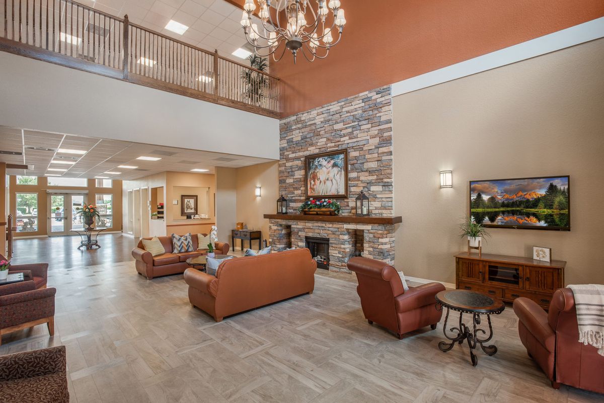 A spacious lobby with comfortable seating, a stone fireplace, and a chandelier.
