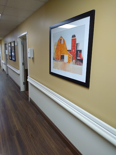 A hallway featuring a colorful framed artwork against yellow walls, complemented by wooden flooring.
