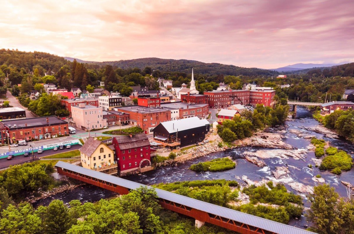 A picturesque town with historic buildings by a river at sunset.
