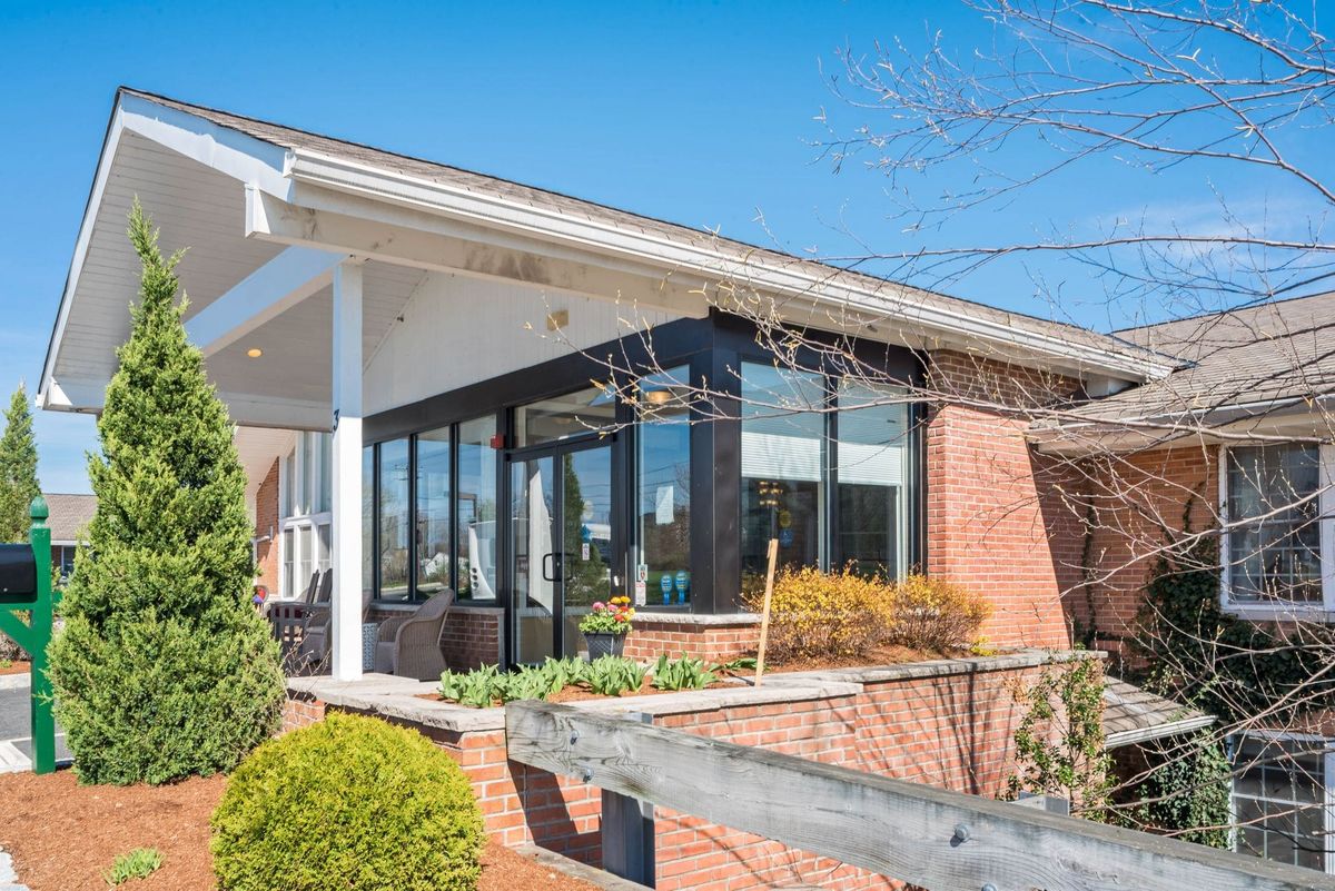 A modern restaurant with large glass windows and a brick exterior surrounded by greenery.