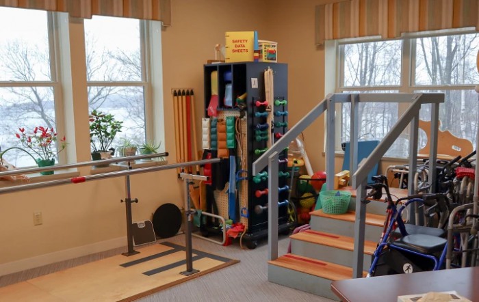 A physical therapy room equipped with exercise tools and parallel bars.