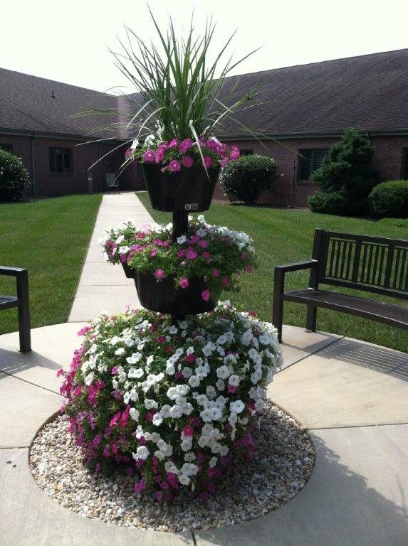 A tiered flower arrangement in a courtyard surrounded by benches.