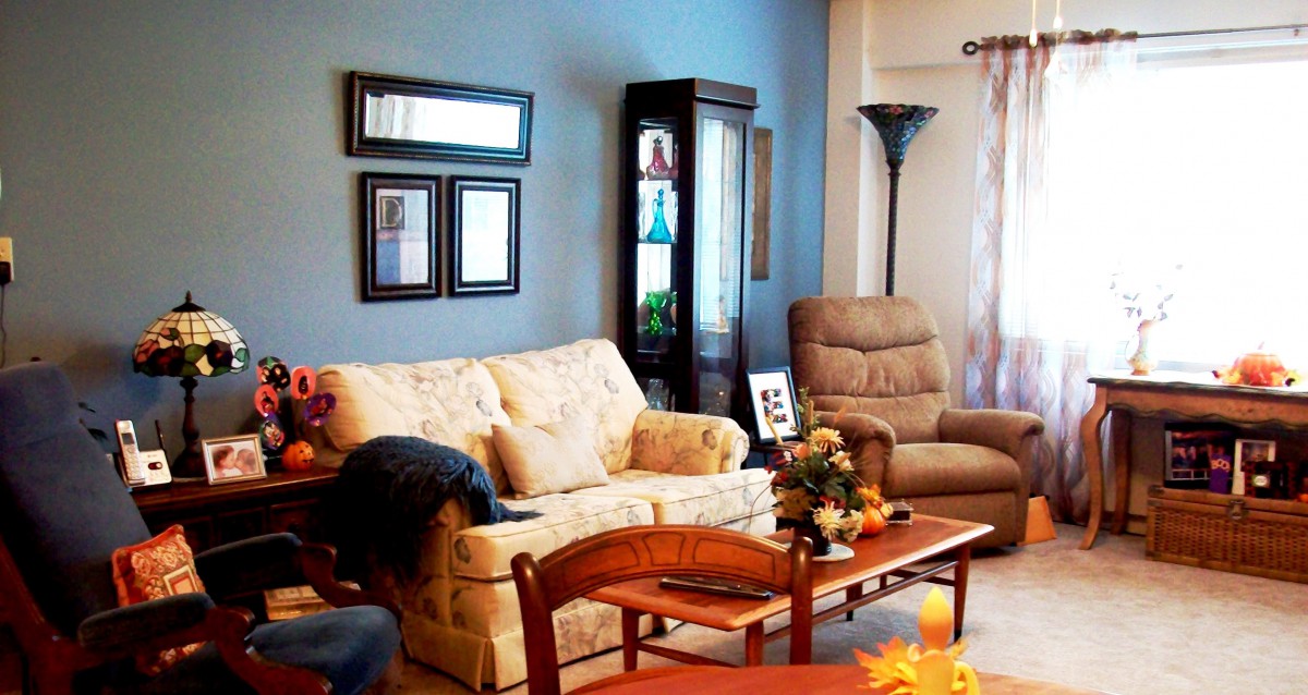 A cozy living room with a sofa, armchair, and wooden coffee table, set against a blue accent wall.
