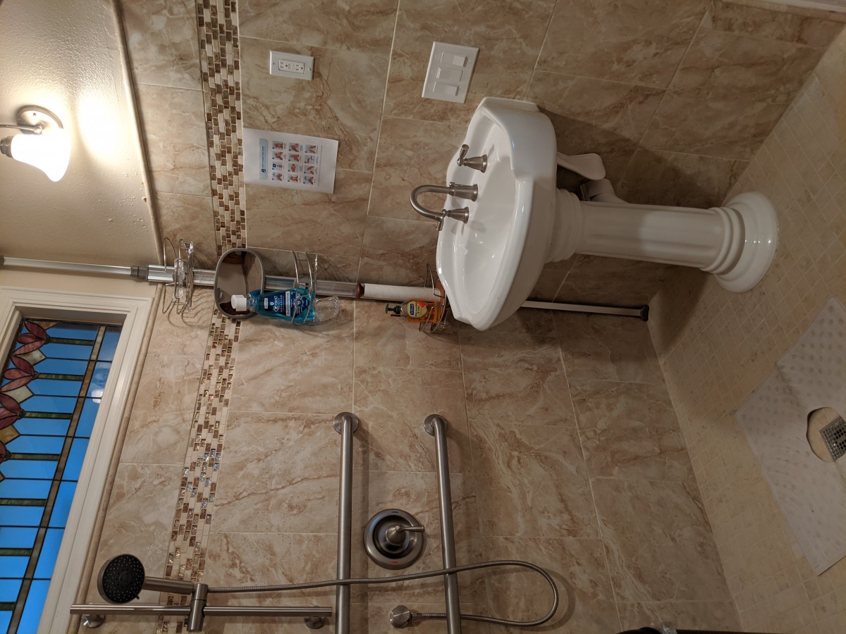 A bathroom featuring a pedestal sink, tiled walls, and safety grab bars.