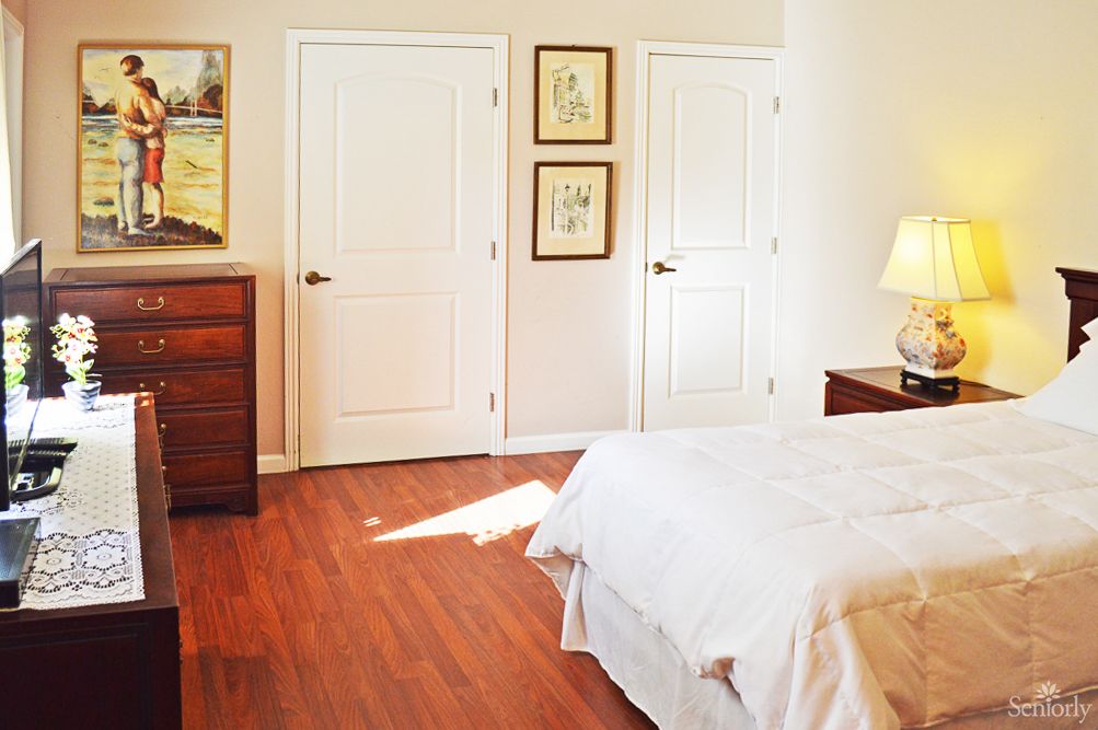 A cozy bedroom with a wooden floor, featuring a bed and dresser.