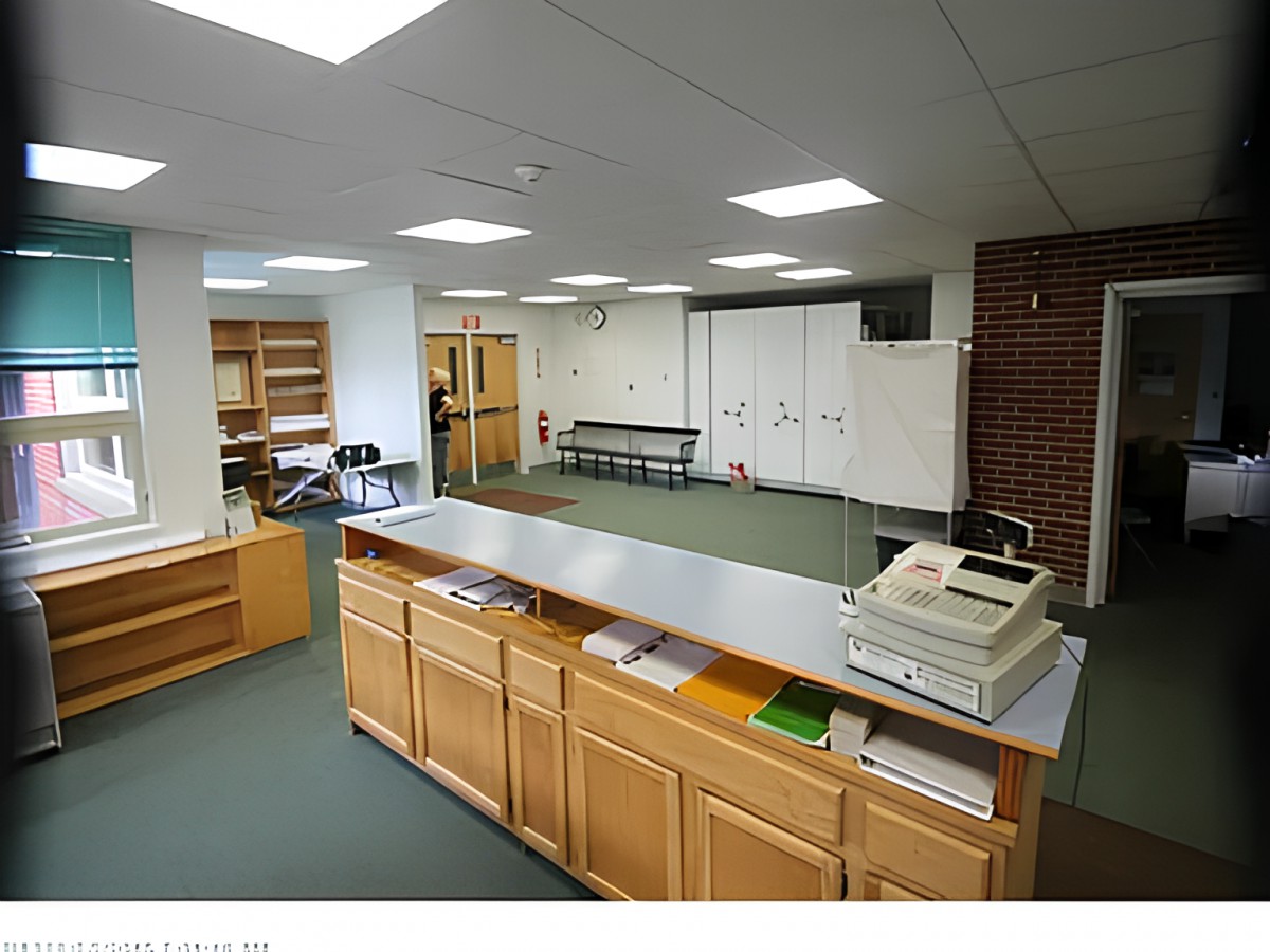 A reception area with a desk and waiting space, featuring office furniture and shelving.
