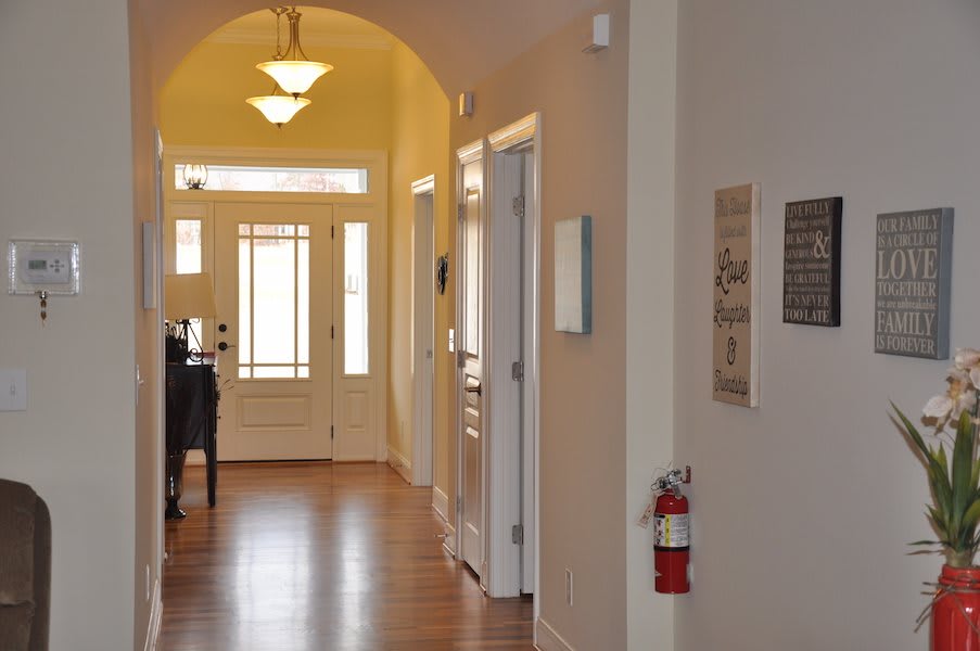 A well-lit hallway with wooden flooring leading to a door.