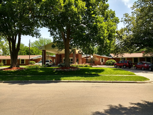 A serene residential setting featuring a well-maintained building surrounded by lush greenery.
