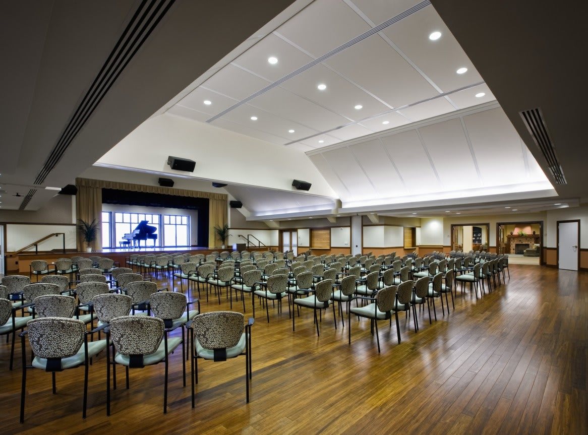 An empty conference room with rows of chairs facing a stage.
