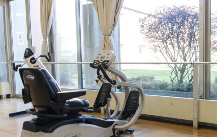 An exercise bike in a well-lit gym with large windows.
