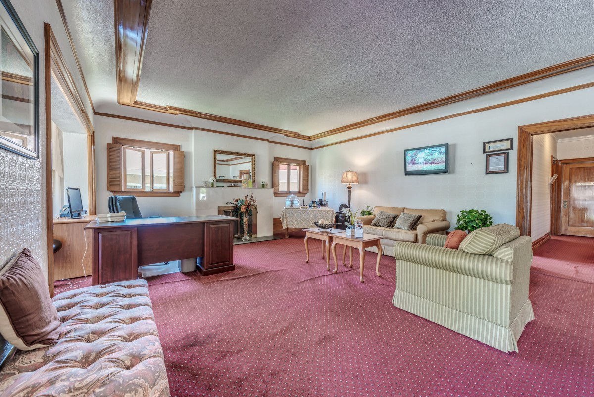 A spacious office room with a large desk, multiple sofas, and elegant decor.