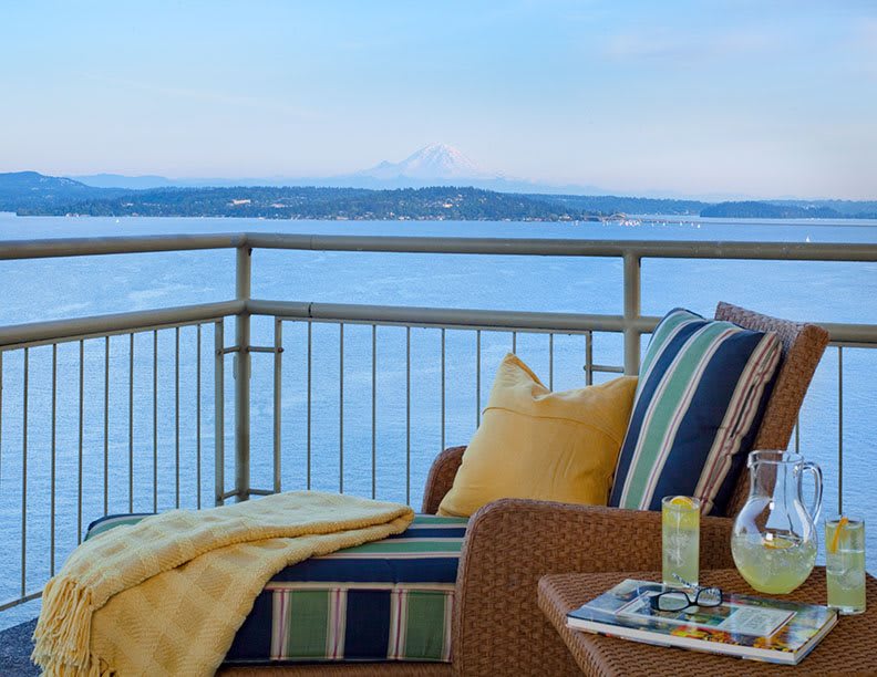 A cozy balcony setup with cushions overlooking a serene ocean view.