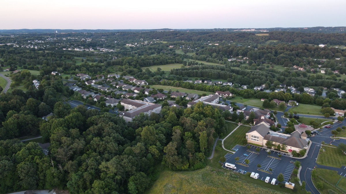 A scenic aerial view of a suburban neighborhood surrounded by lush greenery and open fields.
