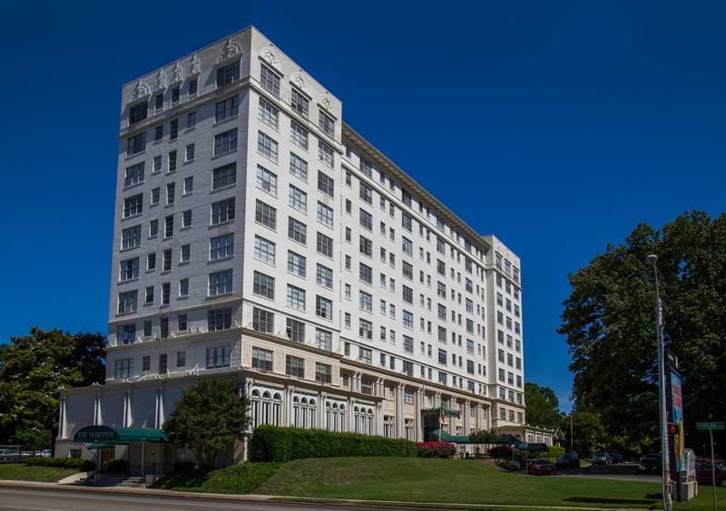 A large white residential building stands tall against a clear blue sky.