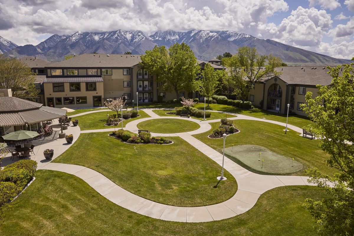 A scenic campus courtyard surrounded by buildings, with pathways and a backdrop of mountains.