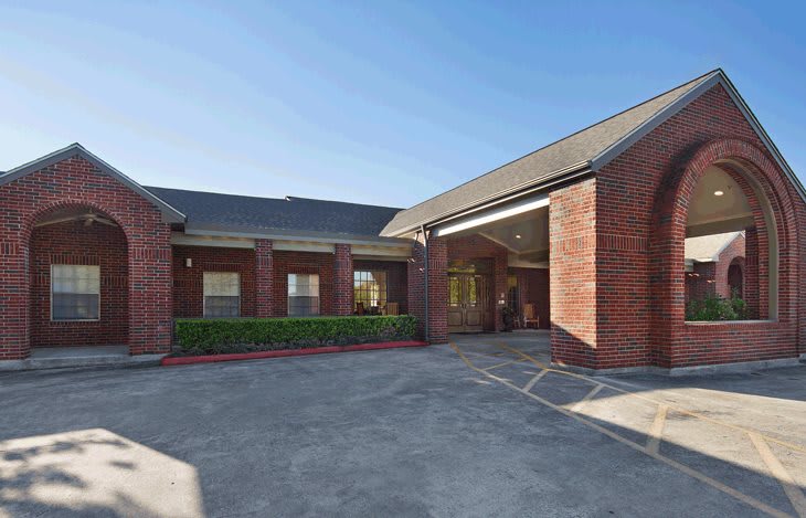A brick building with an entrance and a driveway under a clear blue sky.