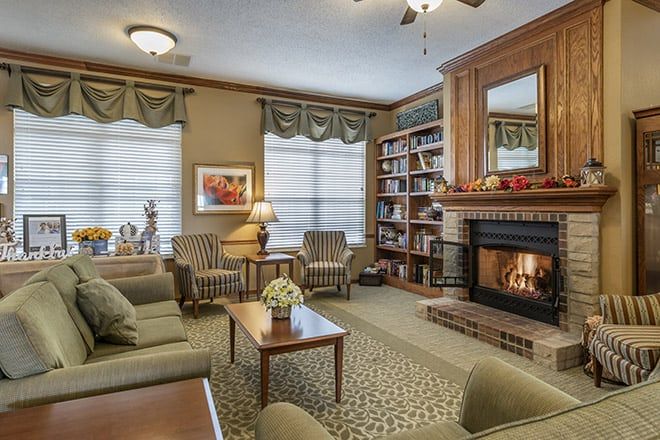 A cozy living room featuring comfortable seating, a warm fireplace, and bookshelves filled with books.