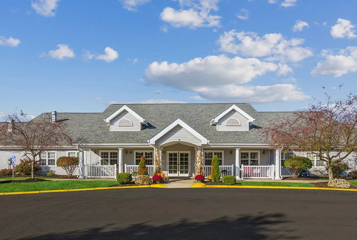 A suburban house with traditional architecture and a landscaped front yard under a blue sky.