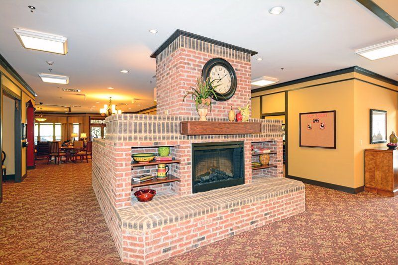 A cozy brick fireplace adorned with a clock and decorative items in a warmly lit living room.