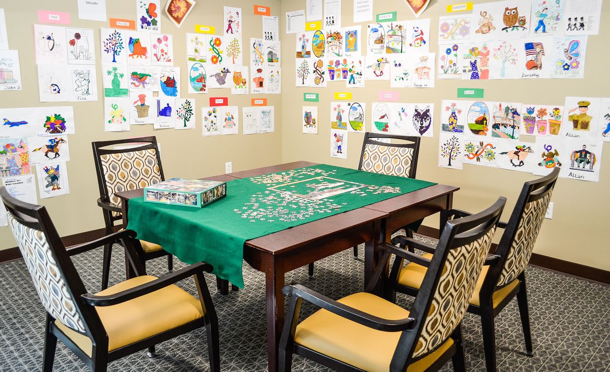 A cozy game room with a puzzle set up on a table, surrounded by chairs and colorful artwork on the walls.