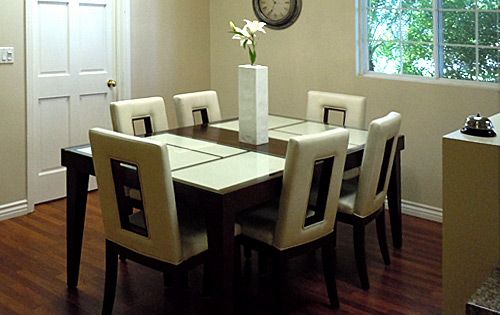 A modern dining room with a wooden table, six upholstered chairs, and a decorative vase centerpiece.