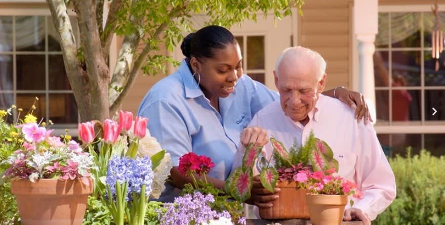 Two people tending to flowers in a garden setting.