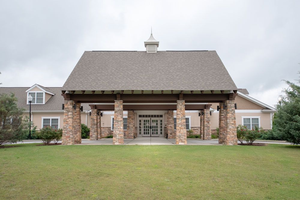 A stone-faced building with a large entrance supported by columns and surrounded by landscaped grass.