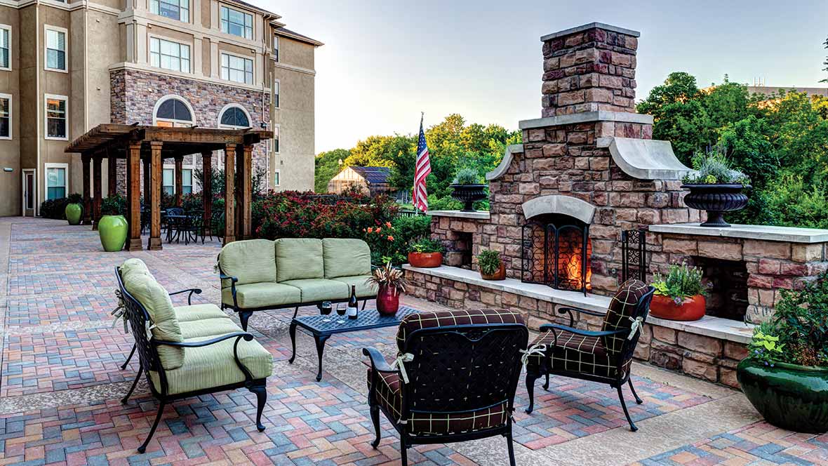 A cozy outdoor patio with a stone fireplace and comfortable seating.