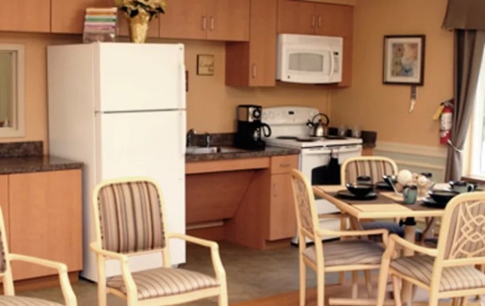 A cozy kitchen with dining area, featuring appliances like a refrigerator, microwave, and oven.
