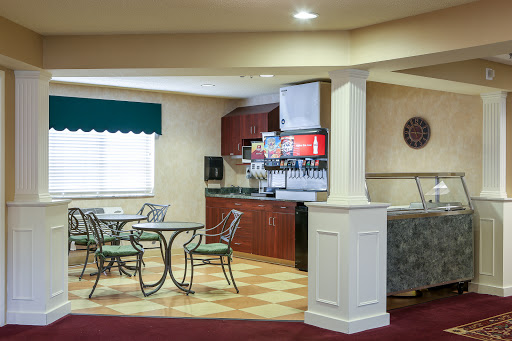 A cozy breakfast area featuring a dining table, chairs, and a beverage station in a well-lit environment.