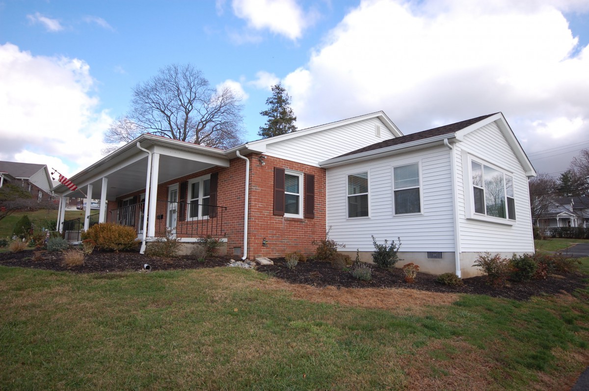 A suburban house with a brick and white exterior under a cloudy sky.