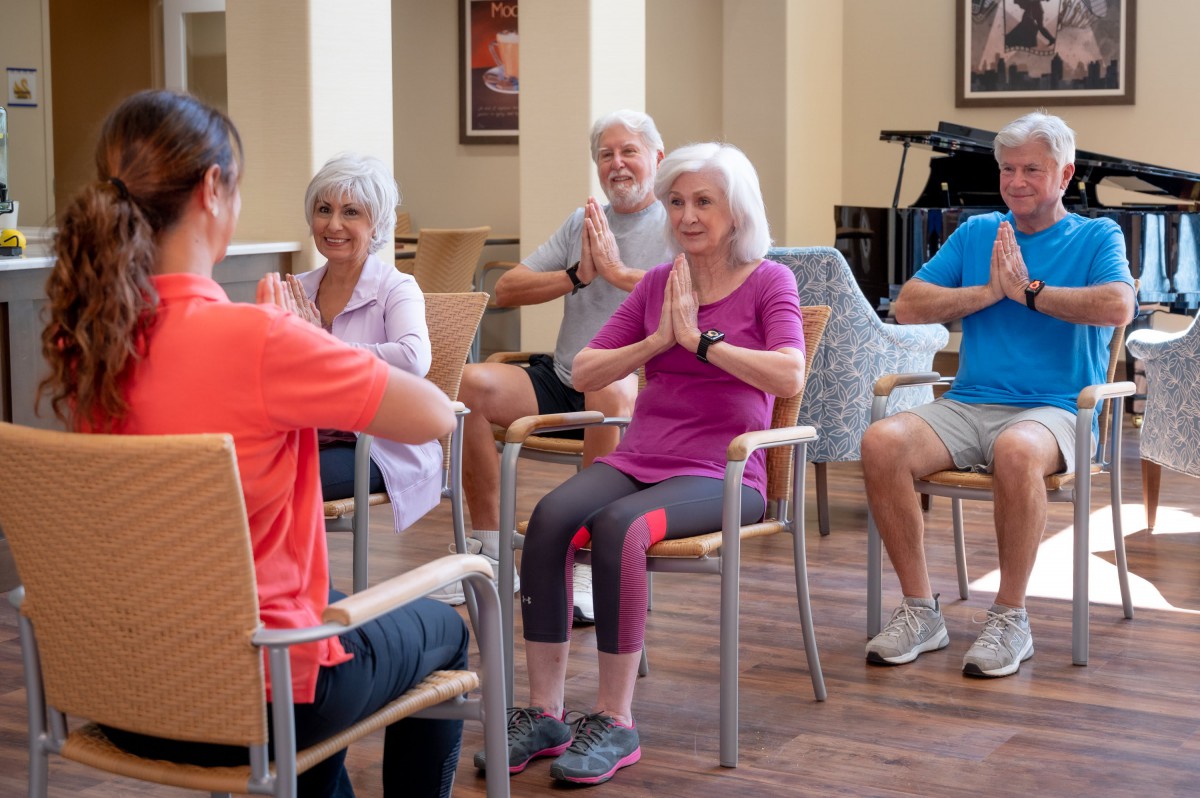A group of seniors participating in a seated yoga class, engaging in meditation and mindfulness.