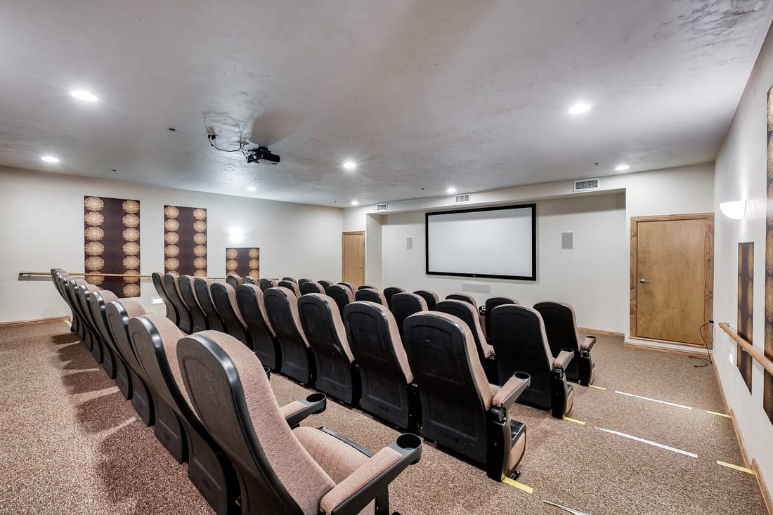 A cozy home theater with multiple rows of seating facing a large projection screen.