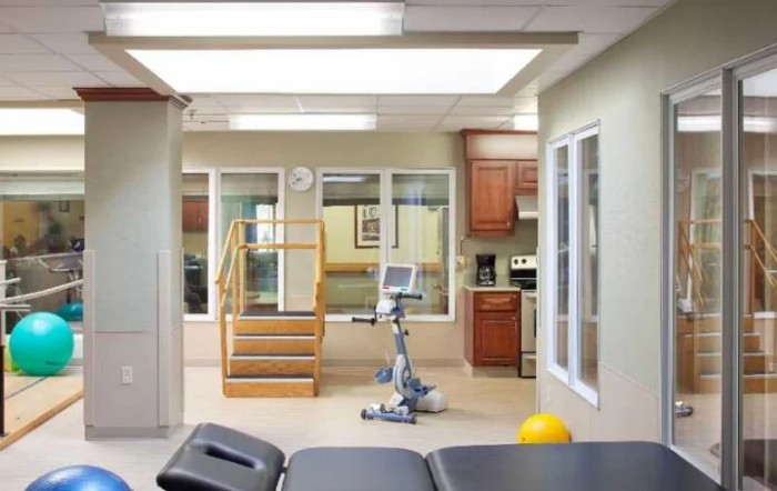 A rehabilitation therapy room with exercise equipment and a staircase.