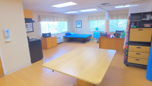 A spacious and well-lit room featuring a table, workspace, and rest area.