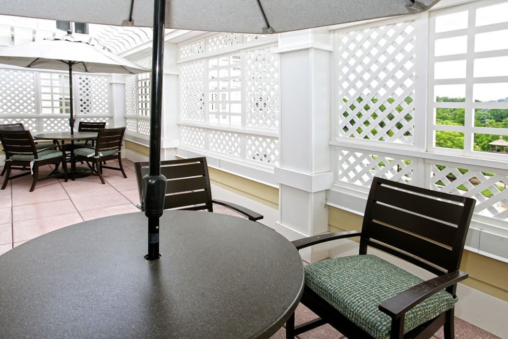 A cozy outdoor patio area with tables, chairs, and umbrellas surrounded by lattice fencing.
