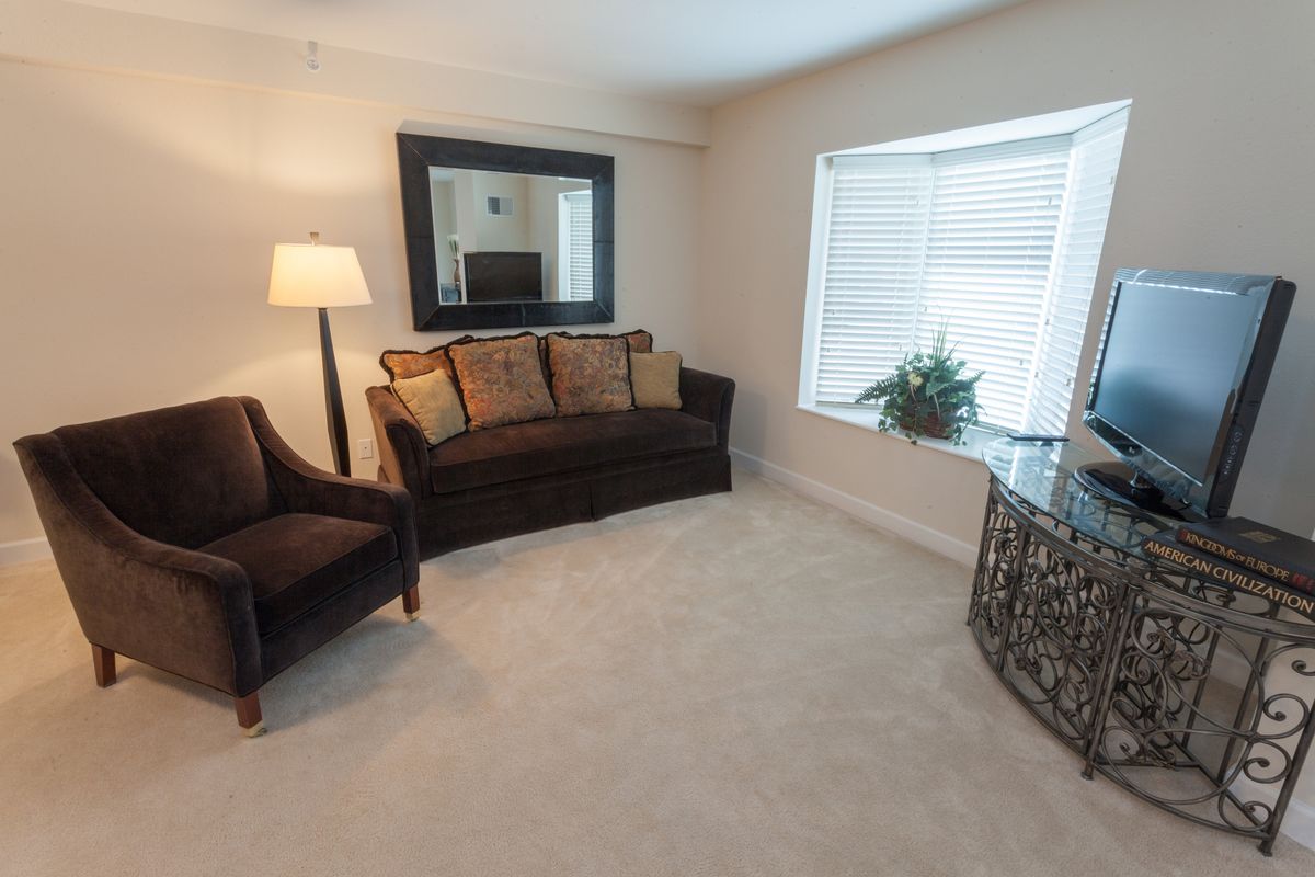 A cozy living room with a sofa, armchair, and a large mirror on the wall.